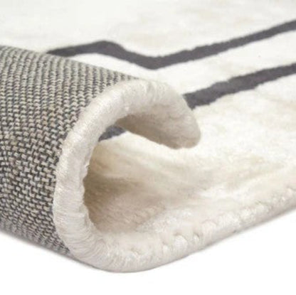 Close-up of a textured rug with a white and gray pattern on a white background