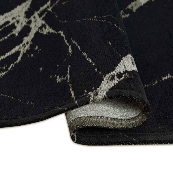 Close-up of a black and gray patterned rug corner on a white background