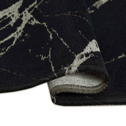 Close-up of a black and gray patterned rug corner on a white background