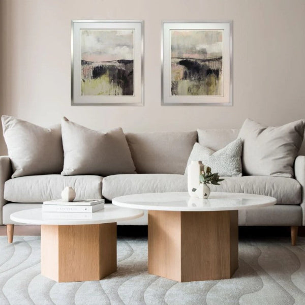Modern living room with a gray sofa, round wooden coffee table, and abstract wall art.