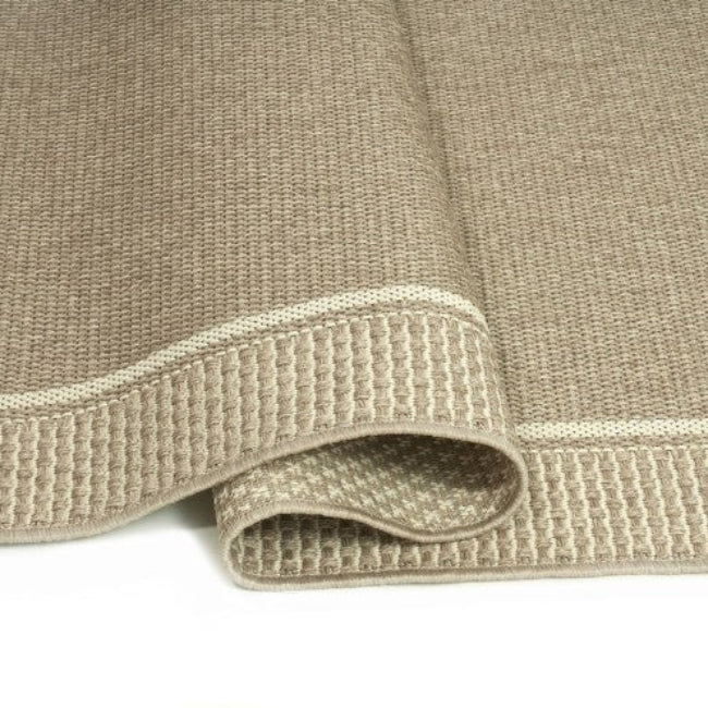 Close-up of a textured beige rug with a ribbed border.