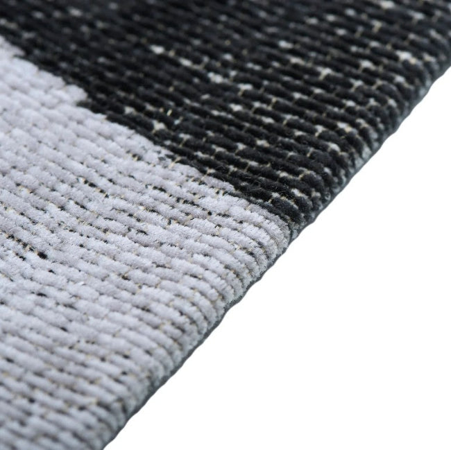 Close-up of a textured black and gray rug corner on a white background