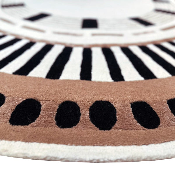 Close-up of a round rug with black and white concentric circles and a brown border.