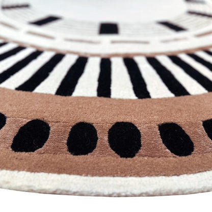 Close-up of a round rug with black and white concentric circles and a brown border.