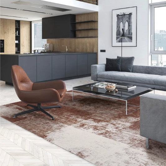 Modern living room with gray sofa, brown armchair, and kitchen area.