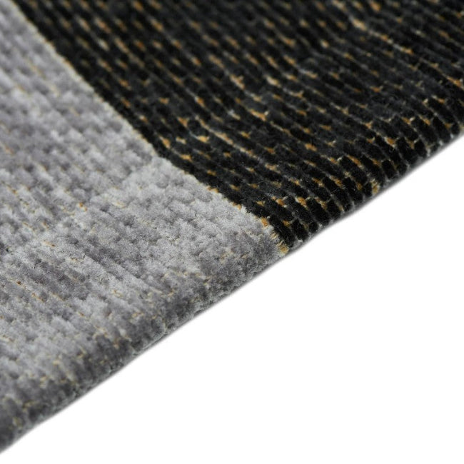 Close-up of a textured gray and black rug corner on a white background