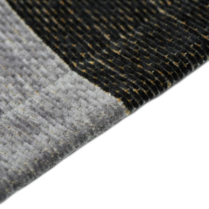 Close-up of a textured gray and black rug corner on a white background