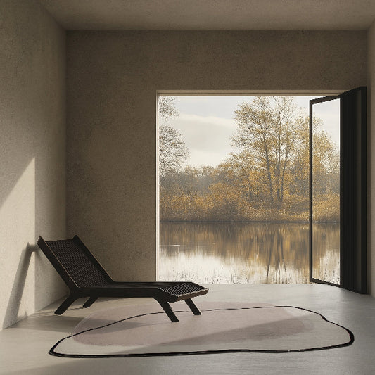 Modern room with a black lounge chair and large window overlooking a lake and trees.