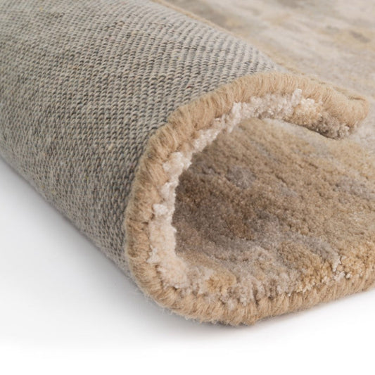 Close-up of a rolled-up beige and brown rug on a white background
