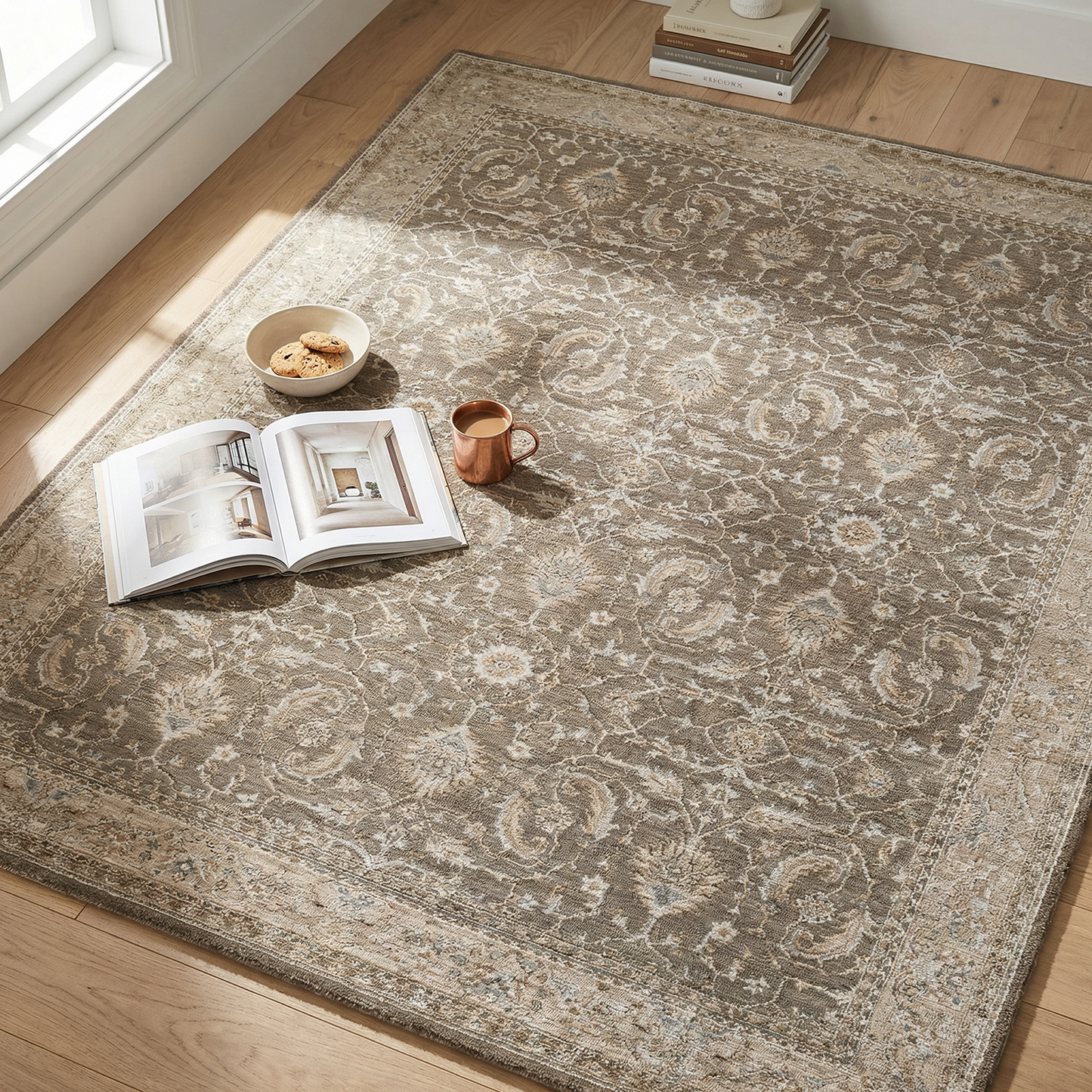 Patterned rug on a wooden floor with books and a cup