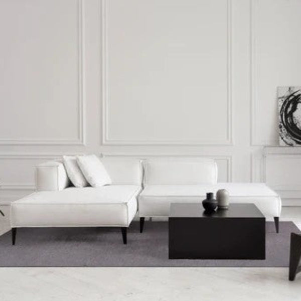 Modern living room with white sofa, black coffee table, and abstract art on wall.