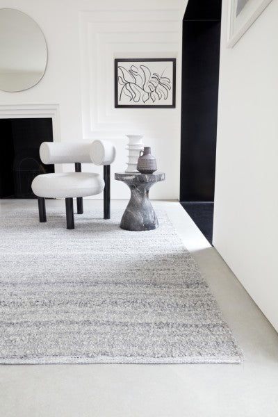 Luxury Boho Abbus Rug by Asiatic in a modern minimalist living room with a white chair and black stone side table