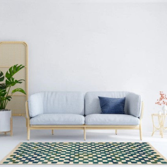 Light gray sofa with a blue pillow in a room with a geometric rug and plant.