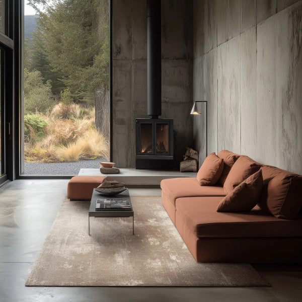 Modern living room with brown sofa, coffee table, and fireplace with a view of nature outside.