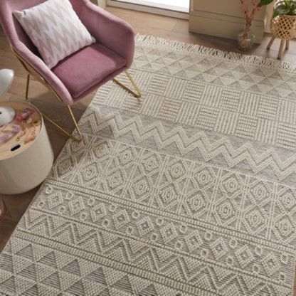 Concept Looms Anya Rug luxury beige geometric pattern rug with fringed edges under pink armchair