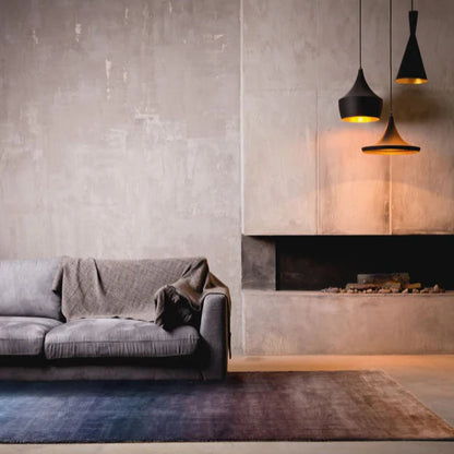 Modern living room with gray sofa, rug, and concrete wall.