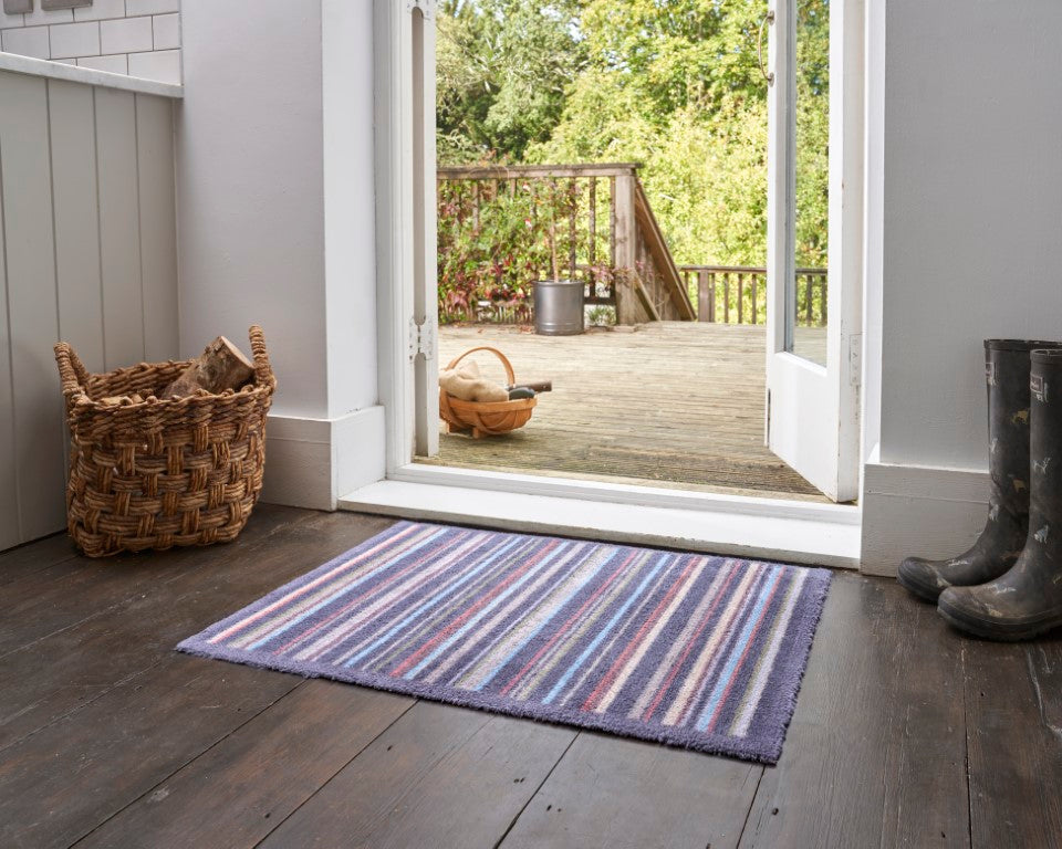 Turtle Mat striped floor mat in a doorway with a rustic outdoor view, adding style to interiors