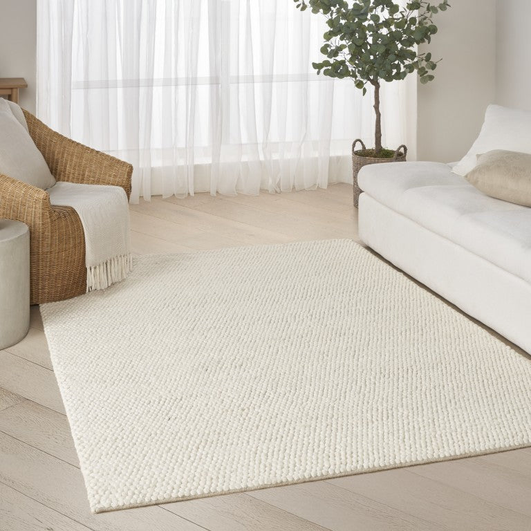 The DKNY Pure Knots Rug Collection in a beautiful neutral setting with a modern sofa and greenery