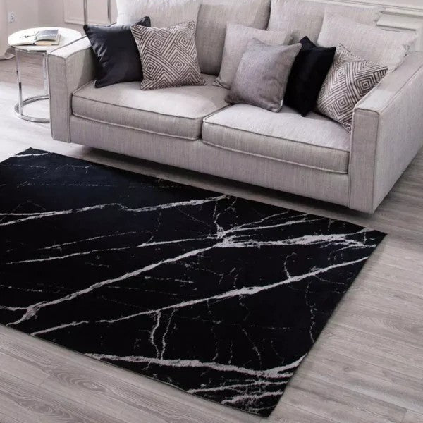 Gray sofa with patterned cushions in a living room setting, featuring a black marble effect rug.