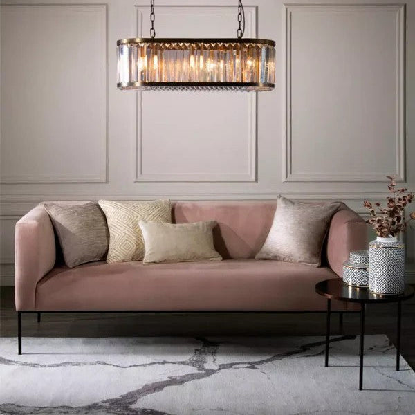 Pink sofa with decorative pillows in a stylish room with a chandelier and side table.