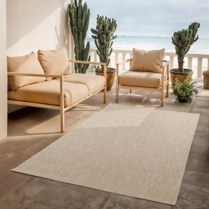Outdoor patio with beige furniture, rug, and cacti on a sunny day.