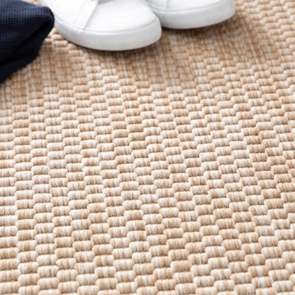 Close-up of a textured beige surface with a dark fabric corner and white shoes.
