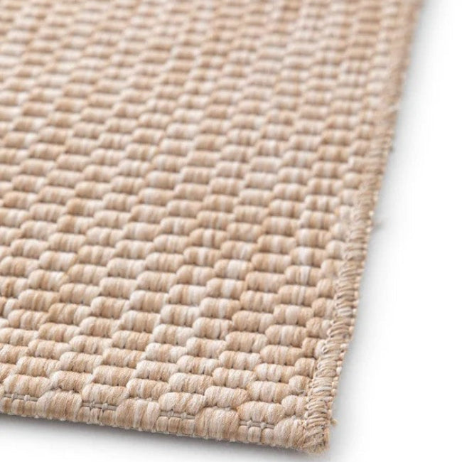 Close-up of a woven beige rug on a white background