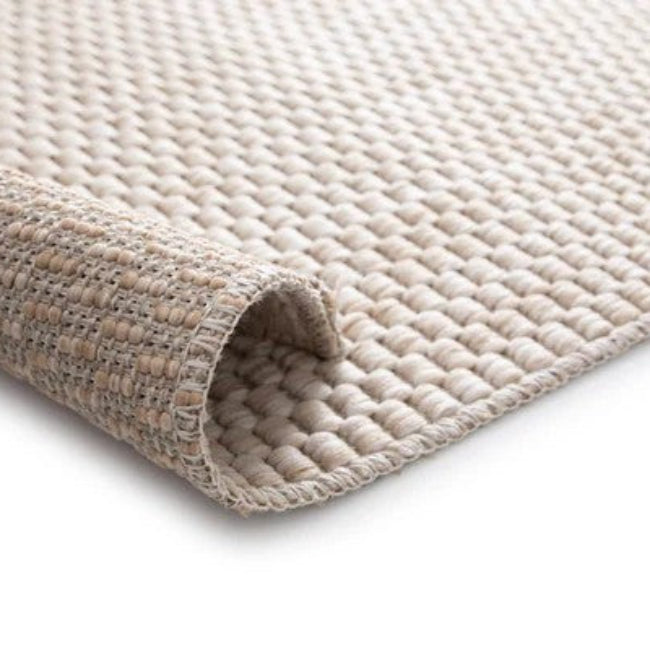 Close-up of a textured beige rug corner on a white background