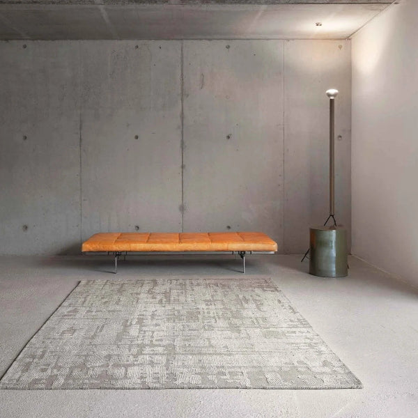 Modern living room featuring a Louis De Poortere Baobab rug in neutral tones beneath an orange bench and floor lamp