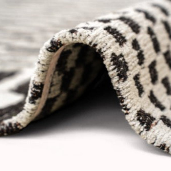 Close-up of folded Louis De Poortere Berber Rug showing soft texture and black and white pattern