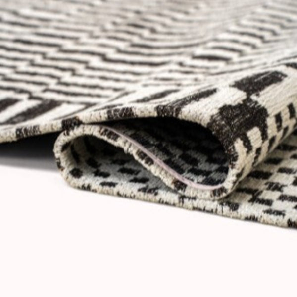 Folded luxury Louis De Poortere Berber Rug featuring intricate black and white geometric patterns