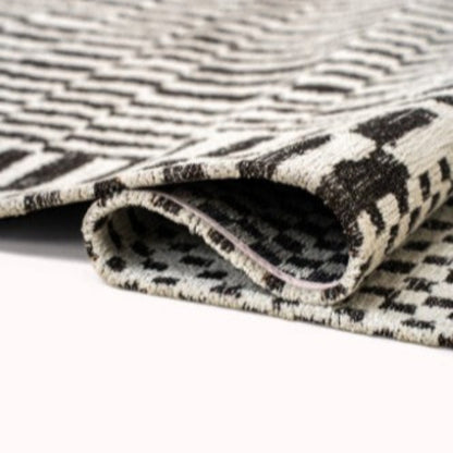 Folded luxury Louis De Poortere Berber Rug featuring intricate black and white geometric patterns