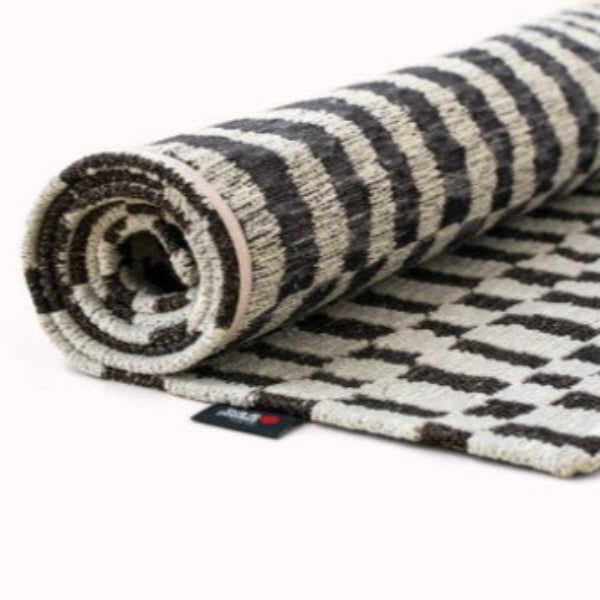 Rolled Louis De Poortere Berber Rug featuring black and white geometric patterns on luxury woven fabric