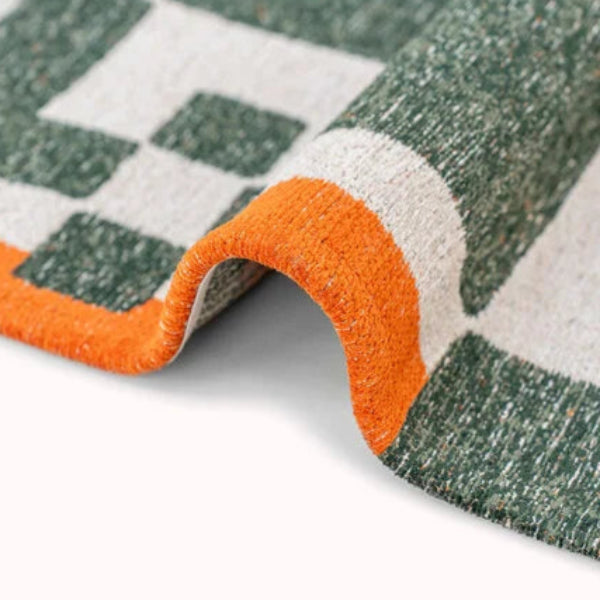 Close-up of luxury Louis De Poortere Chess rug with green, white and orange geometric design