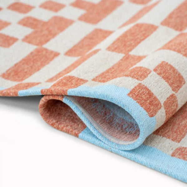 Close-up of folded luxury Louis De Poortere Chess rug with orange and blue checkered pattern