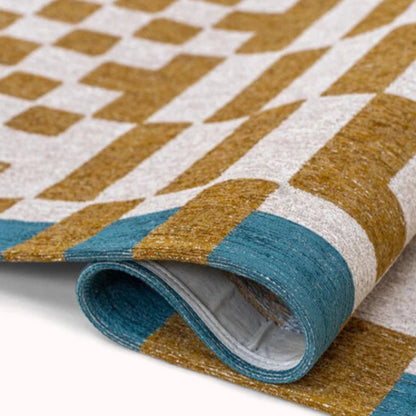 Close-up of a folded Louis De Poortere Chess rug featuring mustard, white, and teal geometric patterns