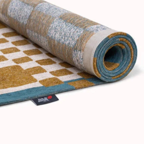 Rolled Louis De Poortere Chess rug with blue and brown checkerboard pattern luxury rug
