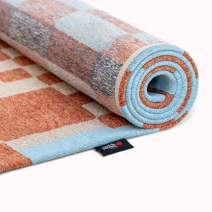 Rolled luxury Louis De Poortere Chess rug featuring a detailed pattern in soft blue and terracotta tones