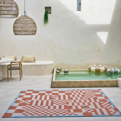 Louis De Poortere Chess rug with geometric chessboard pattern in terracotta and blue in a modern bright room