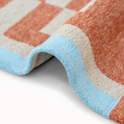 Close-up of textured fabric edge of Louis De Poortere Chess rug in blue beige and terracotta colours