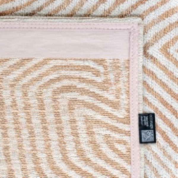 Close-up of Louis De Poortere Coral rug showing detailed beige and white geometric pattern with stitched edges