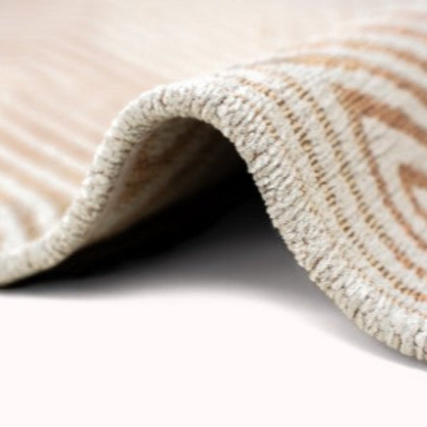 Close-up of a textured beige and light brown Louis De Poortere Coral rug edge showing detailed weaving
