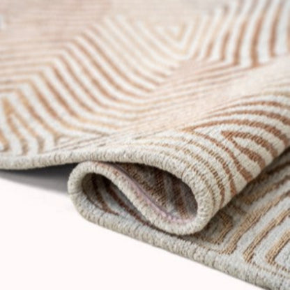 Close-up of folded Louis De Poortere Coral rug showing intricate brown and beige geometric pattern