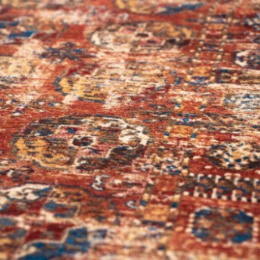 Close-up of a luxurious patterned Louis De Poortere Kasak rug with rich red, blue, and gold colours