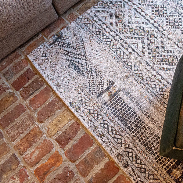 Luxury Louis De Poortere kilim rug with intricate geometric patterns on brick flooring