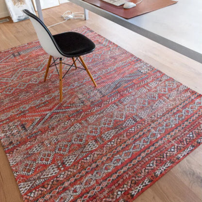 Louis De Poortere kilim rug in red with intricate geometric patterns under a modern chair in office