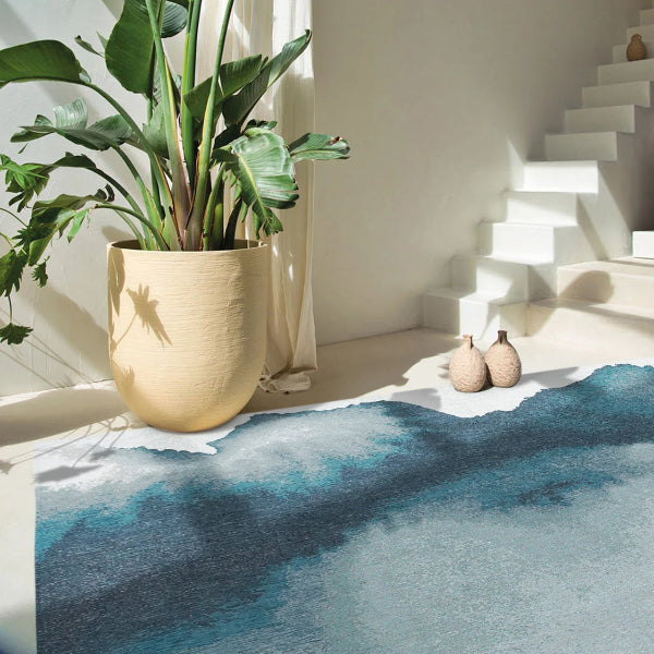 Louis De Poortere Lagoon rug in blue tones displayed in a bright modern room near plants and stairs