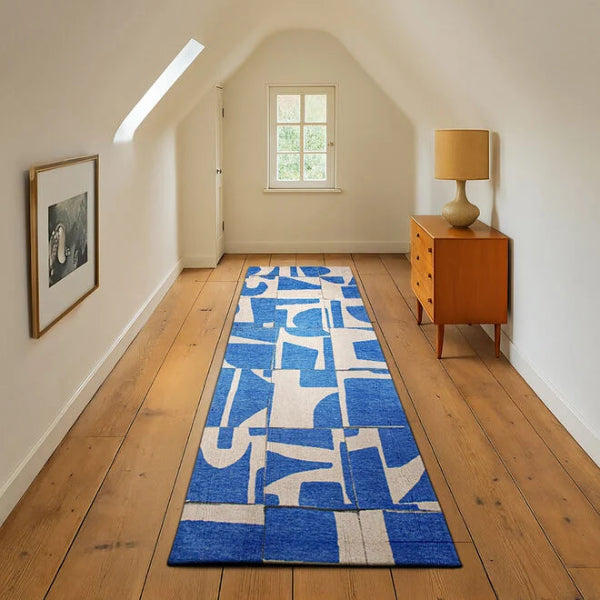 Louis De Poortere Papercut rug in blue and white geometric design on wooden floor in bright hallway