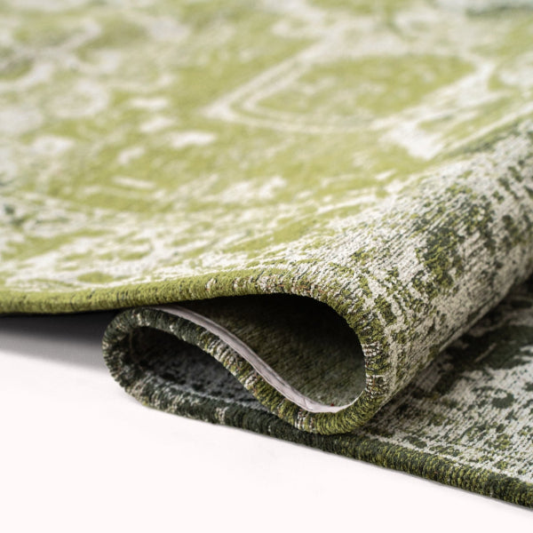 Close-up of folded luxury Louis De Poortere Tabriz rug showing intricate green pattern and texture