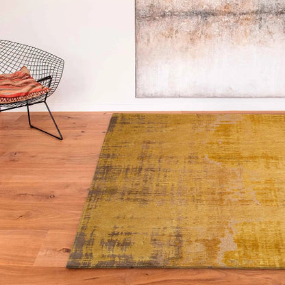 Louis De Poortere Venetian Dust rug in mustard yellow and brown tones on wooden floor with modern wire chair
